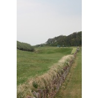 North Berwick Golf Club's famous 13th green, "Pit," features a green tucked between dunes and behind a rock wall. 
